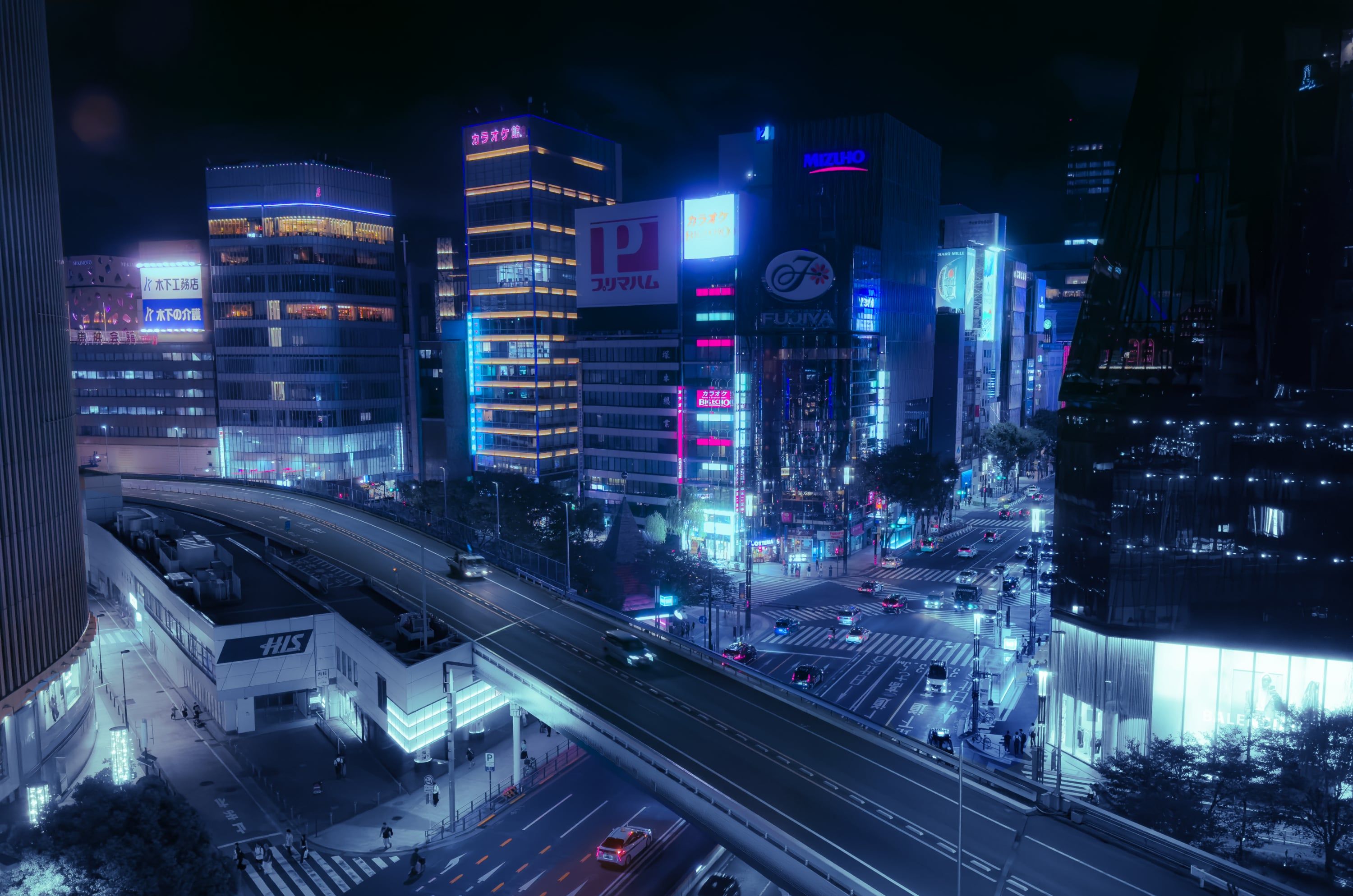 Tokyo at night: neon-lit towers and an elevated highway seen from above