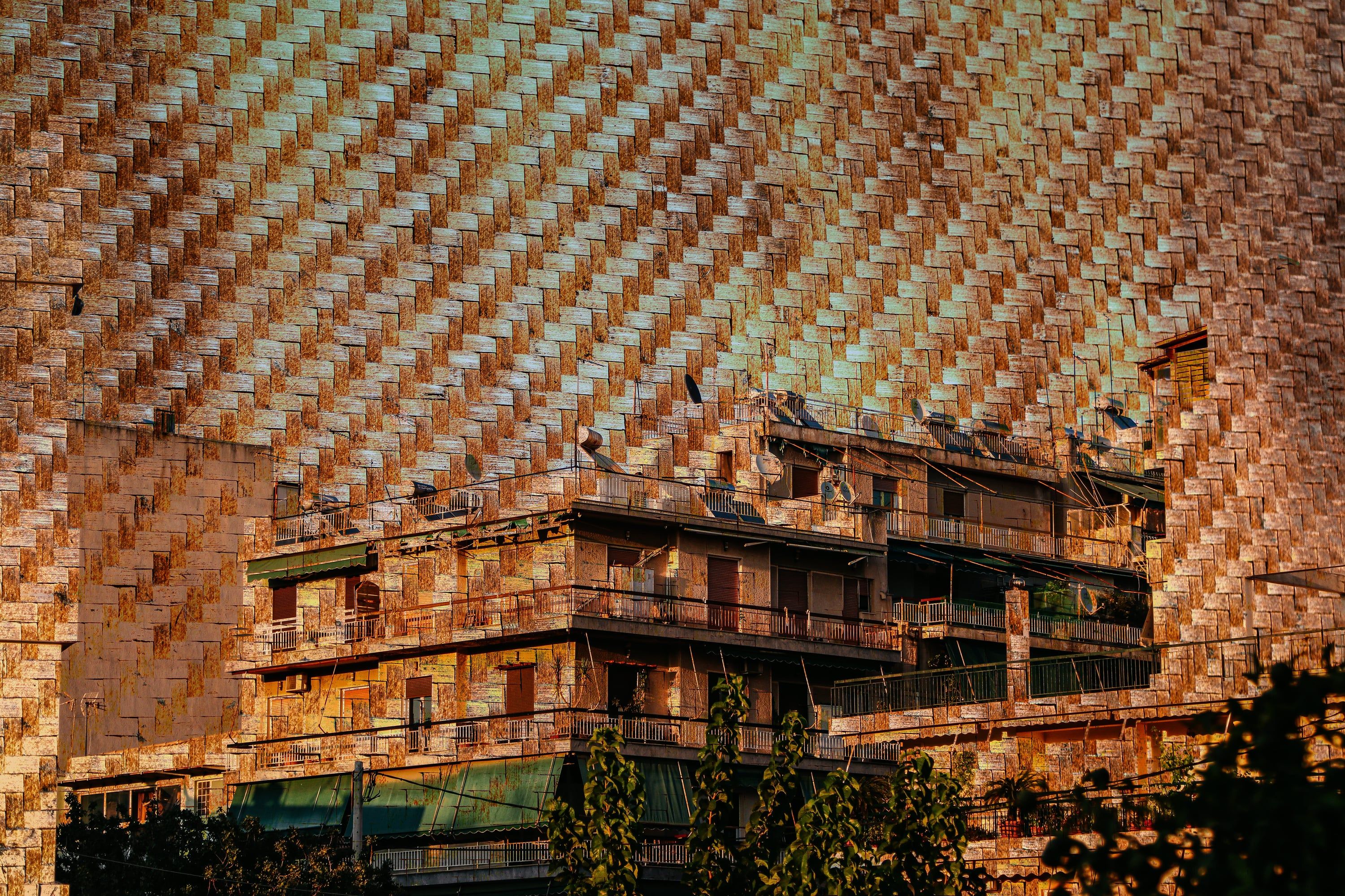 Apartment block glowing in golden light against a woven-texture facade
