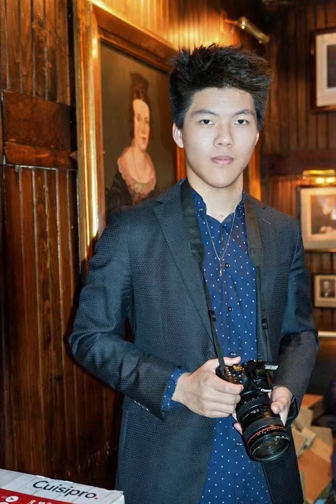 Michael Wang holding a camera in a wood-panelled room